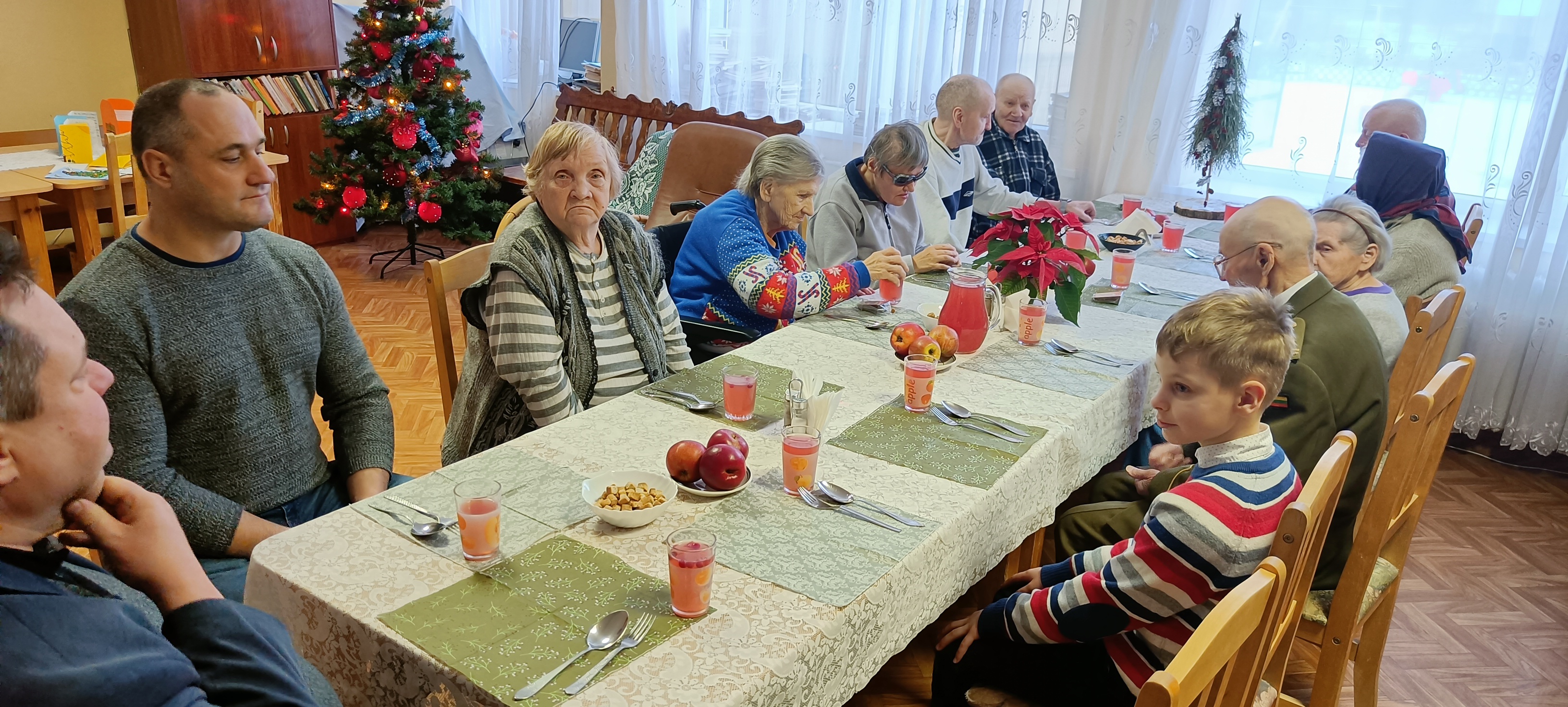 Globos namų gyventojai ir svečiai susėdę prie bendro šventinio stalo