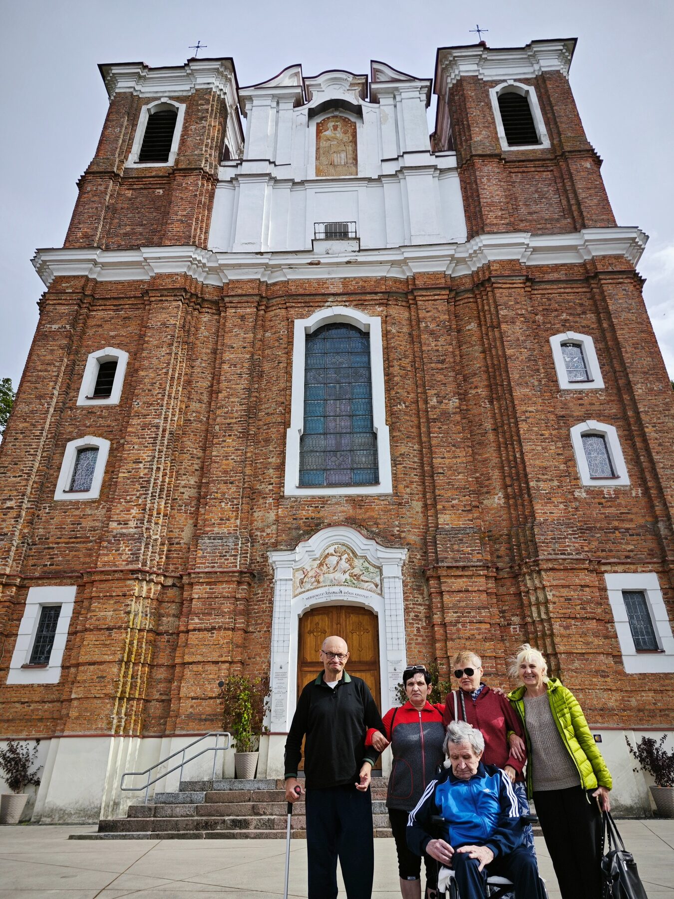 Globos namų bendruomenė išvykos metu prie bažnyčios