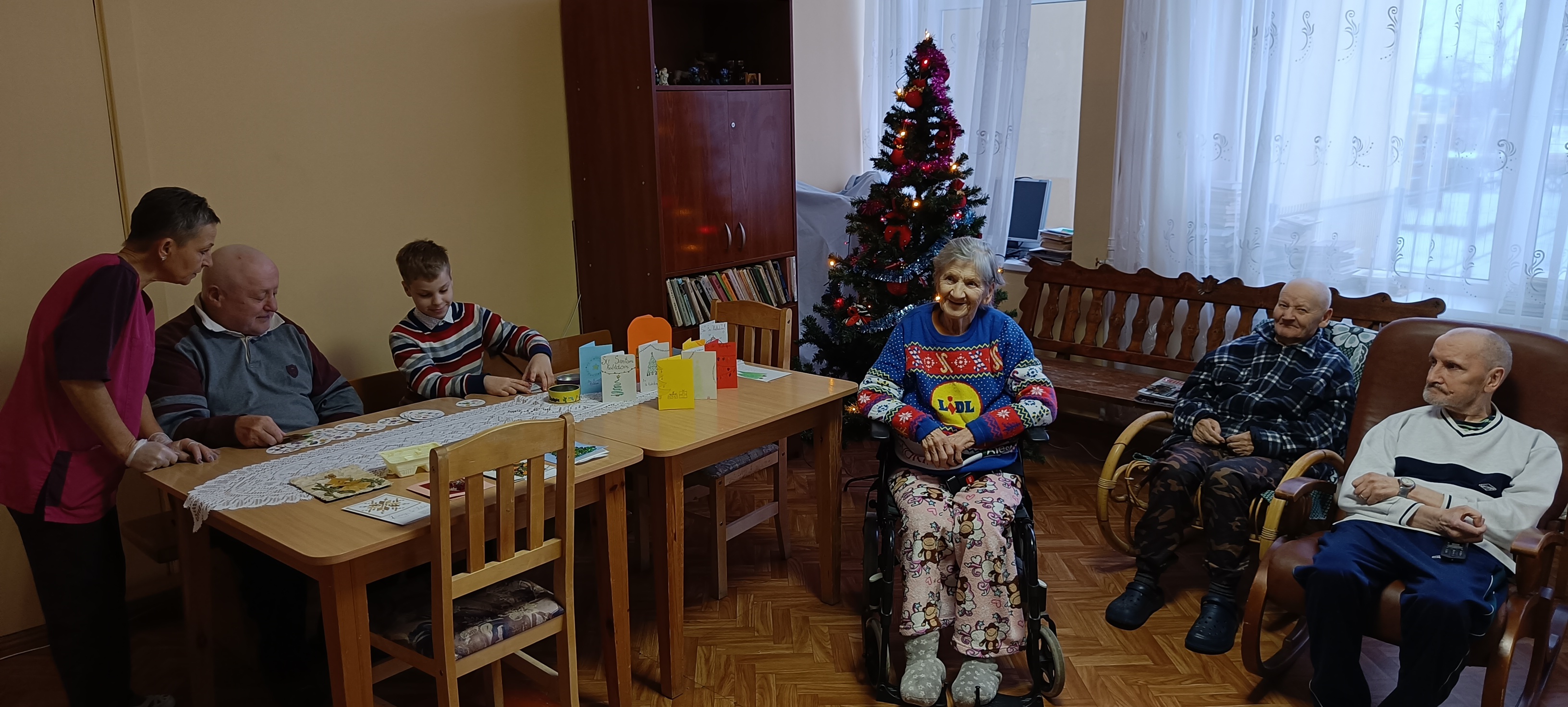 Vaikas ir globos namų gyventojas kartu užsiima kūrybine veikla prie stalo