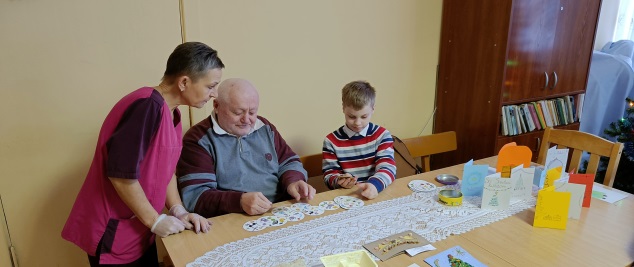 Globos namų gyventojai ir darbuotoja kartu užsiima kūrybine veikla